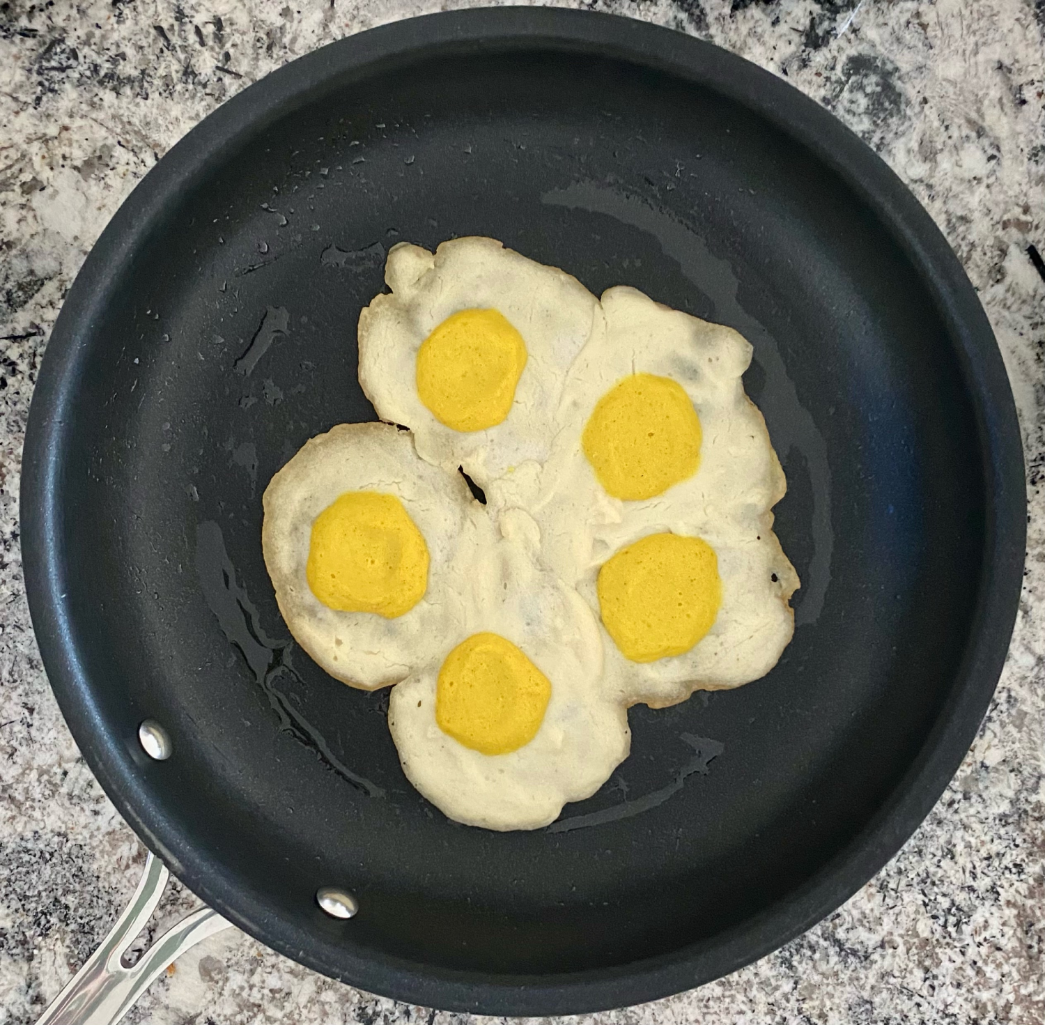 Overhead shot of 5 vegan eggs in a frying pan. 
