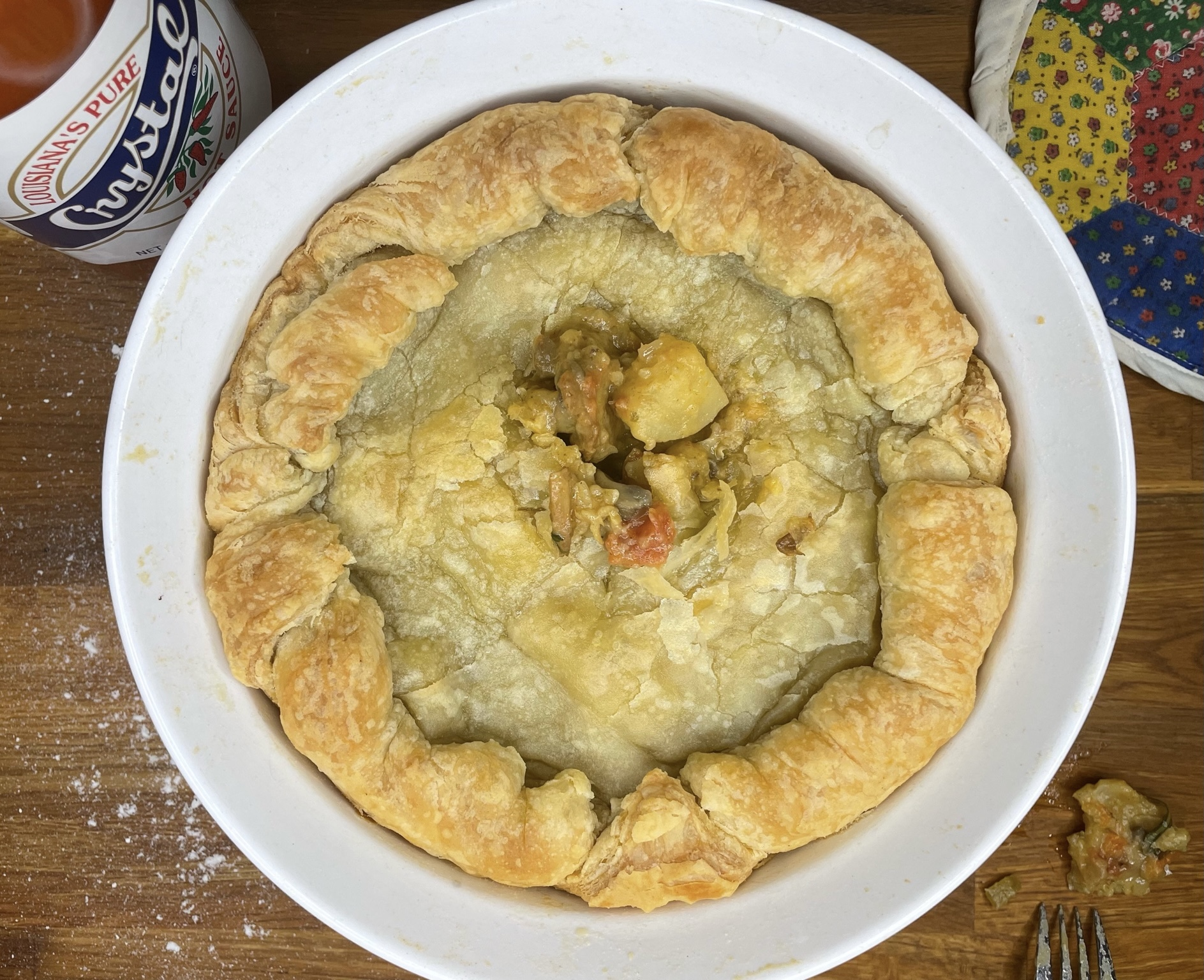 Top down shot of pot pie after it has been broken into with a fork. Crystal Hot Sauce is also in the photo. 